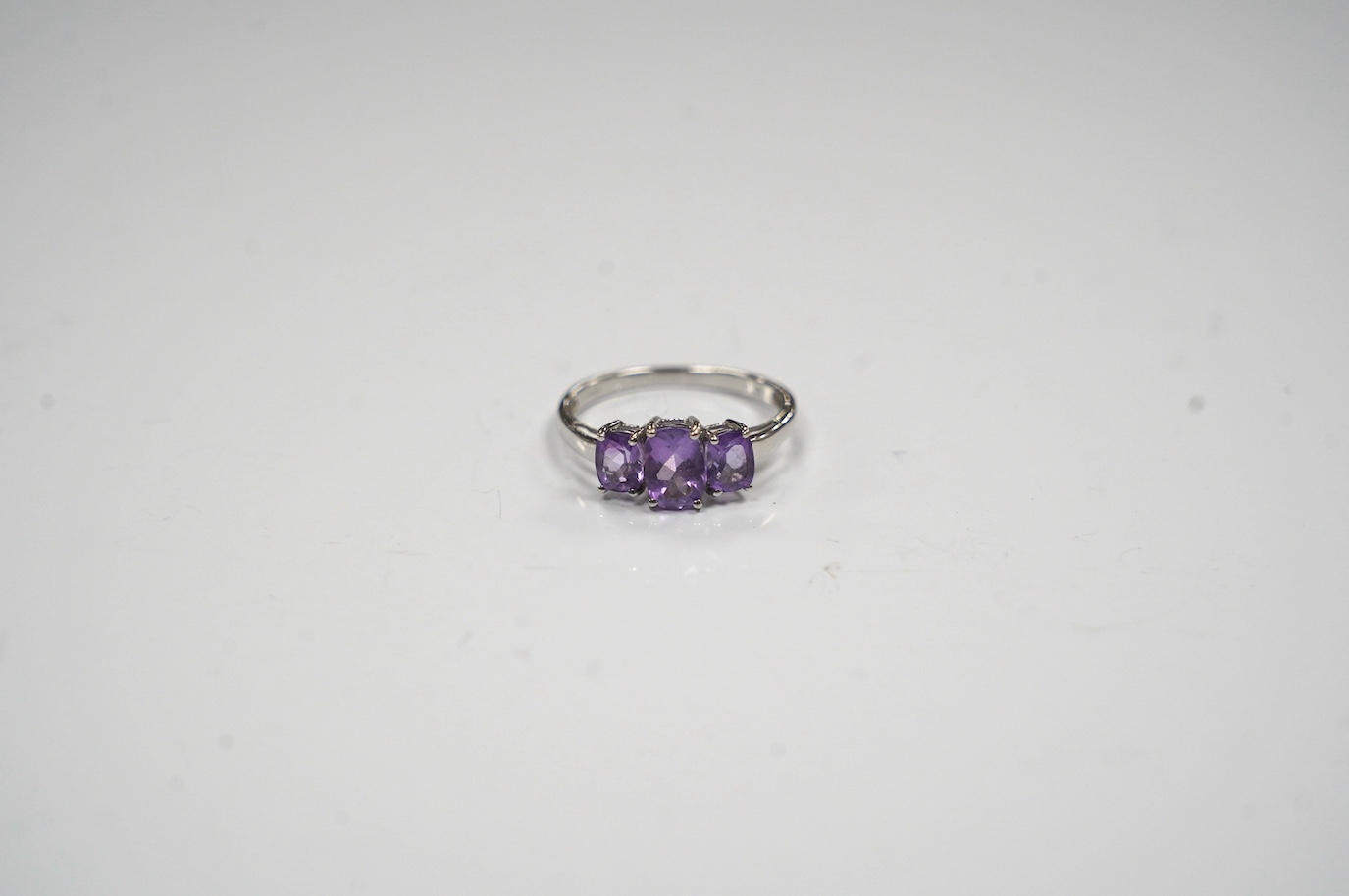 A modern 9ct gold and graduated three stone amethyst set dress ring, size O, gross weight 2.1 grams. Condition - fair to good